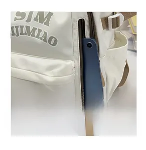 Detail of side zipper pocket on beige nylon backpack holding a blue tablet computer