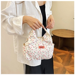 Close-up of floral bento bag featuring pink flowers and a woven red side label