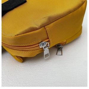 Detail of bright yellow durable nylon fabric and silver metal zipper on kids backpack