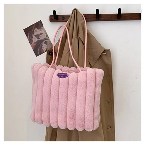 Détail du sac cabas en peluche rose montrant la texture rayée et l'écusson de marque