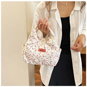 Close-up of floral canvas handbag with pink flower patterns and orange brand label detail