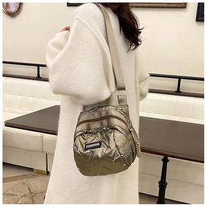 Quilted shell bag in champagne metallic finish shown on shoulder in a cafe setting