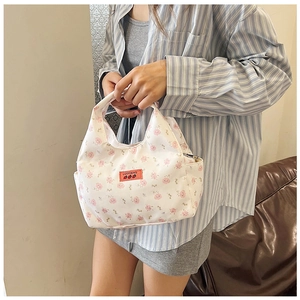 Detailed view of floral pattern handbag with leather logo label and zipper detail