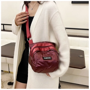 Close-up of wine red quilted shell crossbody bag with adjustable strap and fashion label