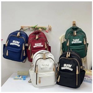 Detail showing various colors of waterproof nylon backpacks with side pockets and zipper