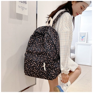 Detail of black floral canvas backpack with zipper front pocket and shoulder strap