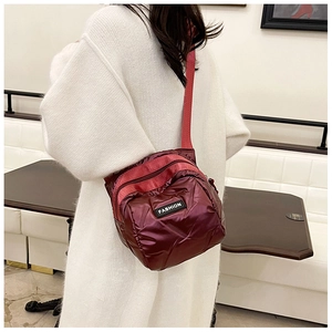 Close-up of wine red puffer crossbody bag with quilted diamond pattern and FASHION tag