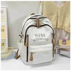 Detail view of the white nylon backpack with multiple zippered compartments and side pockets