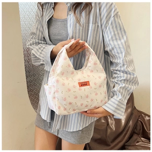 Detail of floral canvas handbag with orange logo label and pink flower patterns