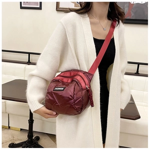 Detail of burgundy padded crossbody bag with multiple zippers and fashion label