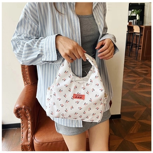 Detailed shot of white floral canvas tote bag with red strawberry patterns and top handle