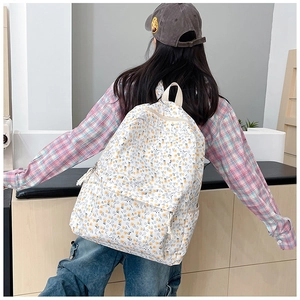 Vue détaillée du dos d'un sac à dos en toile fleurie aux motifs jaunes et bleus