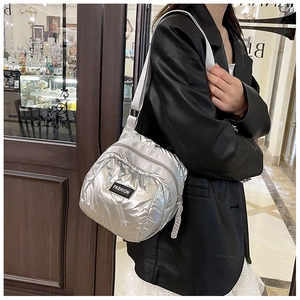 Detailed view of silver quilted crossbody bag with adjustable strap worn by a model