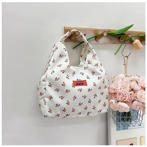 Detail of floral canvas lunch bag hanging on hook with fresh peony flowers