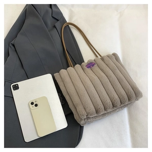 Sac fourre-tout en peluche taupe avec écusson à côté d'une tablette et d'un costume