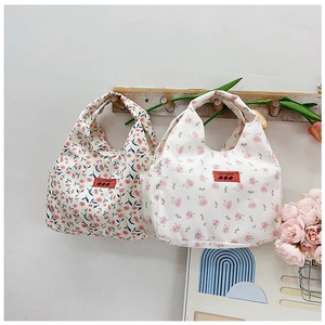 Close-up of floral canvas lunch bag hanging on wooden hook with side pocket detail