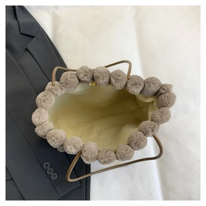 Détail du sac cabas en peluche kaki avec pompons doux et texture de tissu d'hiver chaud