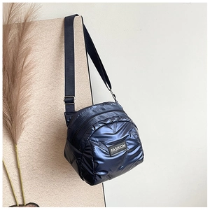 Detail of navy blue metallic quilted crossbody bag with FASHION label and wide strap