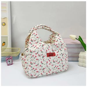 Detail of floral canvas lunch bag featuring side pockets and a red logo woven label