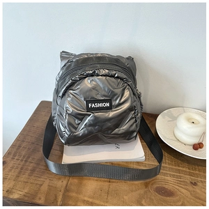 Detail of silver metallic quilted crossbody bag with fashion label on wooden surface