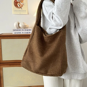 Grote retro donkerbruine fleece draagtas voor dames getoond in een gezellige kamer