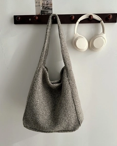 Detailopname van de grijze wollen tweed hobo-tas hangend aan een houten haak