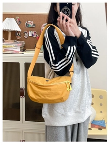 Detail view of a bright yellow casual crossbody bag with double zippers and fabric texture
