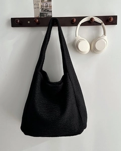Detailopname van zwarte wollen tote bag hobo-silhouet hangend aan een houten haak