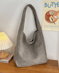 Close-up van grijze wollen tote bag met gebreide textuur in een sfeervolle setting