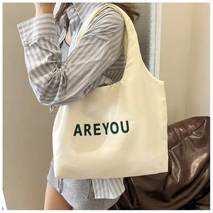 Detalle del bolso tote de lona blanca con texto AREYOU verde y correas anchas