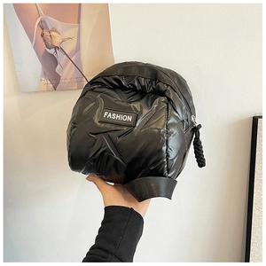 Close-up of black puffer shell bag with quilted texture and thick woven rope zipper pull