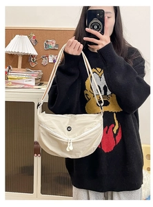 Detail of beige crescent nylon crossbody bag featuring double zippers and a circular OK logo