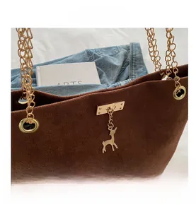 Détail d'un sac cabas en daim marron foncé avec ferrures dorées et poignée en chaîne