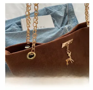 Détail du sac fourre-tout en daim marron avec chaîne dorée et breloque cerf