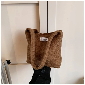 Dettaglio della borsa tote marrone in morbido peluche con etichetta bianca e manici