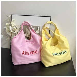 Detalle de bolsos tote en rosa y amarillo con estampados de letras AREYOU en escena de estilo