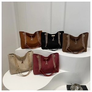 Détail de sacs cabas en suédine colorés avec chaînes dorées et pendentifs de cerf chic