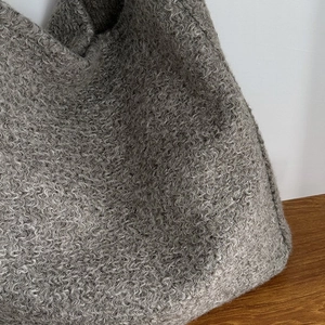 Macro-detail van de donkere taupe bouclé-stof van een grote winterse draagtas