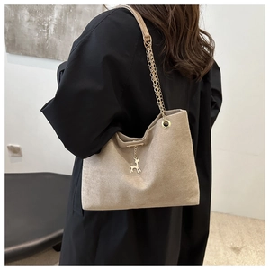 Gros plan d'un sac cabas en daim beige avec chaîne dorée et pendentif cerf chic