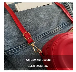 Detail of red PU leather heart bag with adjustable strap and golden metal buckle
