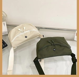 Detail of nylon canvas crossbody bags in off-white and olive green with logo and adjustable straps