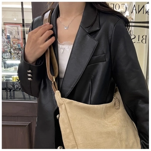 Detail of a large khaki suede tote bag with a wide dark brown leather strap on a model