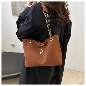 Détail du sac cabas en daim marron avec pendentif cerf doré et bandoulière en chaîne