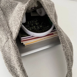 Binnenzicht van grote wollen shopper met laptop, boeken en een witte koptelefoon