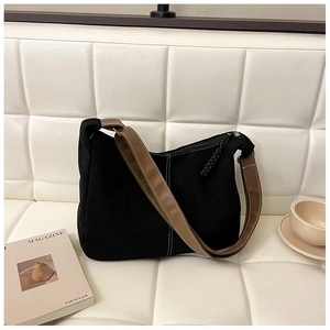 Detail of black suede tote bag with brown leather strap and contrast white stitching