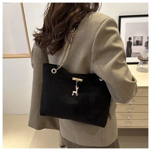 Détail du sac cabas en suède noir avec chaîne dorée et breloque cerf porté par mannequin