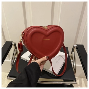 Detail of red heart-shaped crossbody bag featuring fashion & bag logo and golden hardware