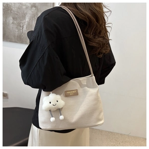 Détail du sac cabas gaufré crème avec étiquette logo cuir et breloque nuage