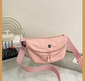 Detail of pink nylon crossbody bag featuring double-way zipper and black QK logo