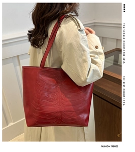 Detalle del bolso tote de cuero rojo con diseño de relieve óseo 3D sobre una gabardina